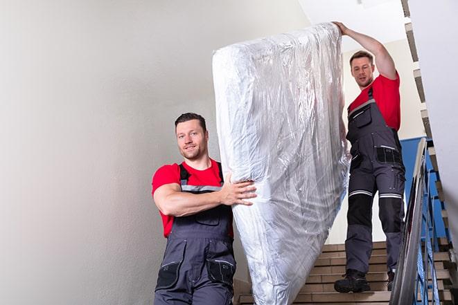 two workers carrying a heavy box spring out of a bedroom in East Fishkill